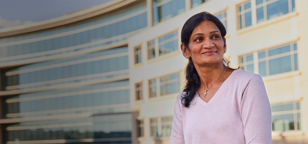 Ramani sitting outside an office building, looking to the side.