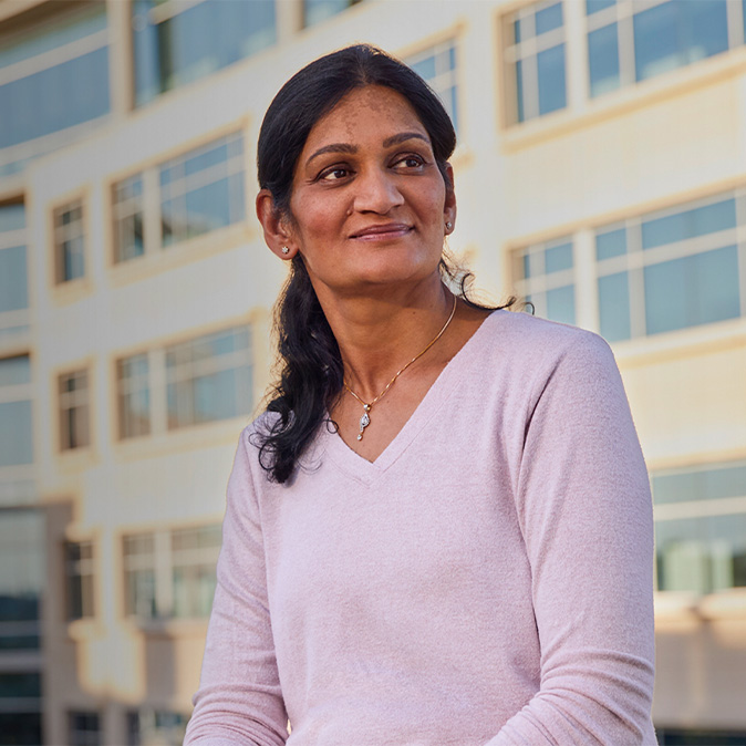 Ramani sitting outside an office building, looking to the side.