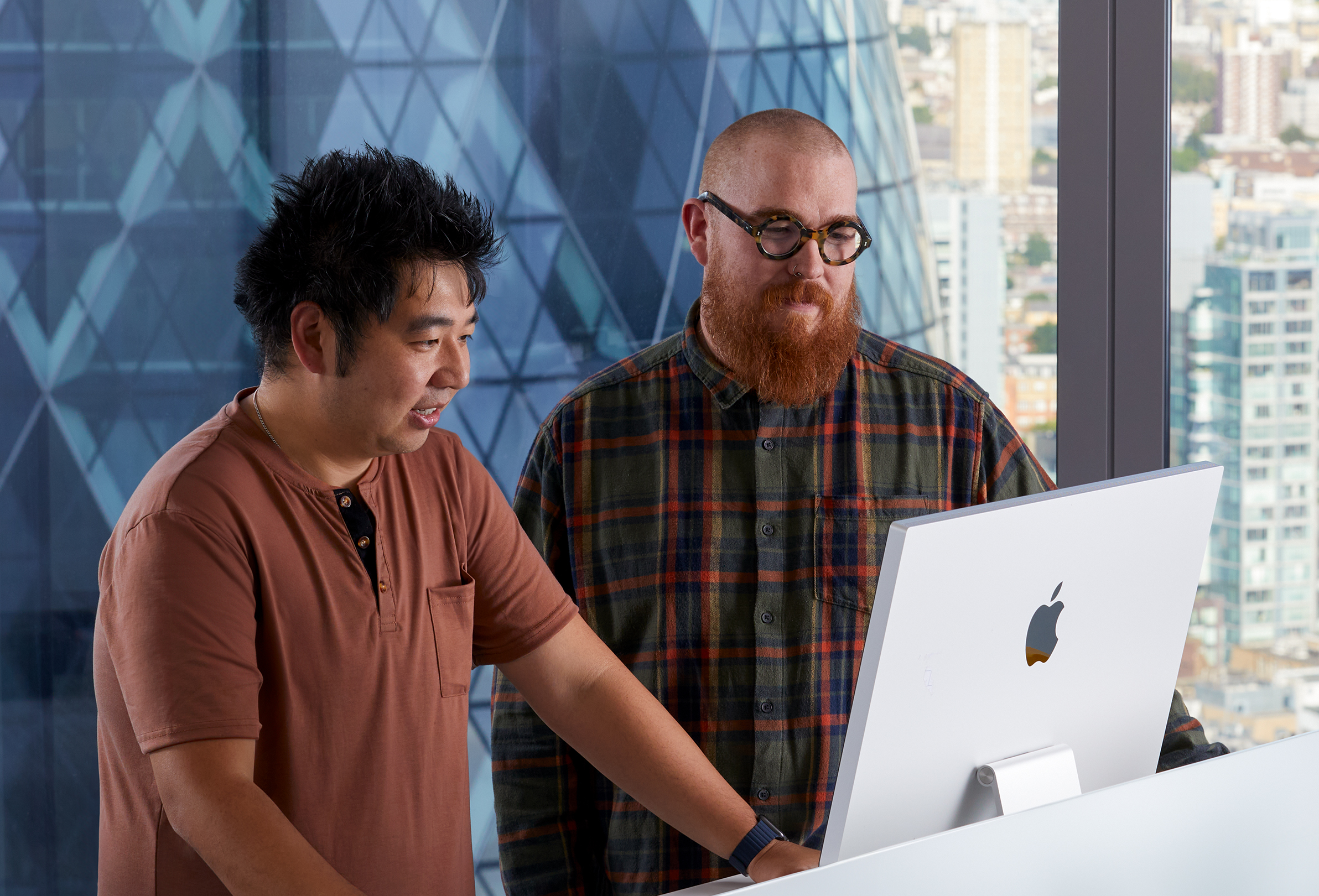 Two Apple colleagues collaborating while using an iMac.