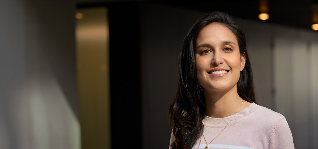 Camila standing indoors, smiling, in an office space.