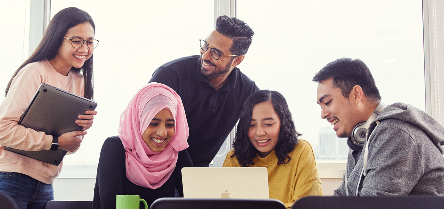 Apple-alkalmazottak gyülekeznek egy megbeszélésre, miközben az egyik munkatársuk MacBookjának képernyőjét nézik.