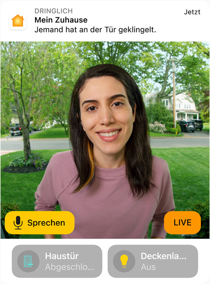 Die Ansicht einer Türklingel-Kamera mit einer Frau in einem rosa Sweatshirt. Das Display zeigt die Wörter „Sprechen“ und „Live“.
