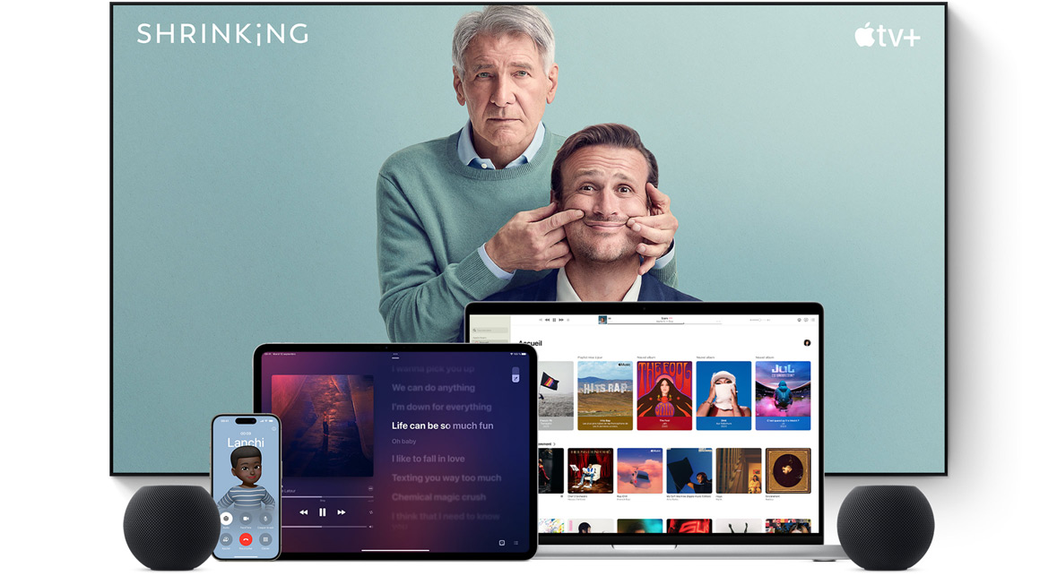 Large flat screen television showing two male characters from the Apple TV+ series shrinking. A MacBook Pro, an iPad, an iPhone, and a Midnight HomePod mini are arranged in front.