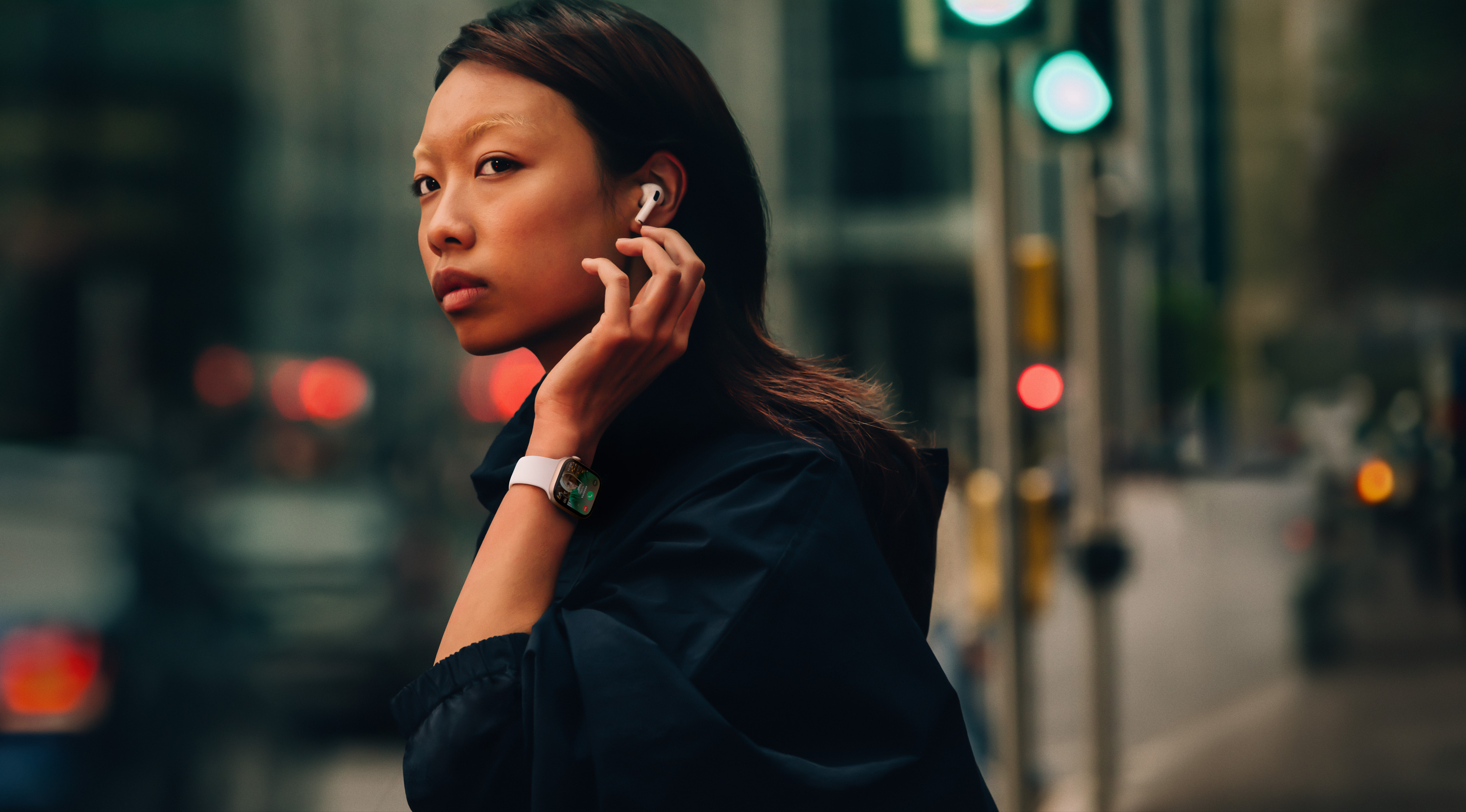 Žena na ulici nosi Apple Watch Series 10 i slušalice AirPods.