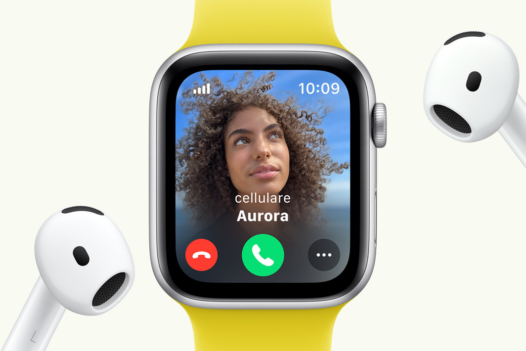 Un Apple Watch SE con una chiamata in arrivo sullo schermo, accanto a un paio di AirPods