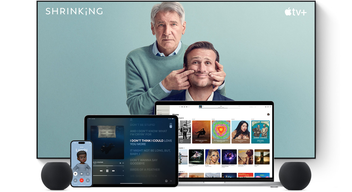 Large flat screen television showing two male characters from the Apple TV+ series shrinking. A MacBook Pro, an iPad, an iPhone, and a Midnight HomePod mini are arranged in front.