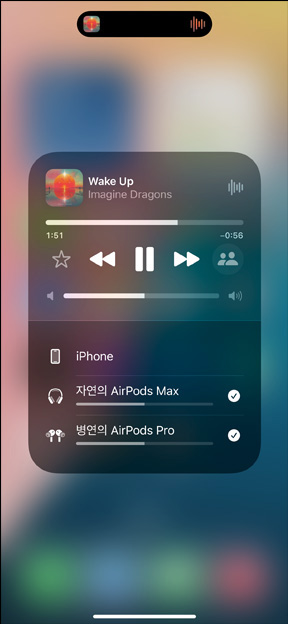 충전 케이스 안에 든 AirPods Pro와 iPhone이 나란히 있는 모습. iPhone은 개별적인 음량 제어가 가능한 두 개의 AirPods 세트와 연결되어 있습니다.