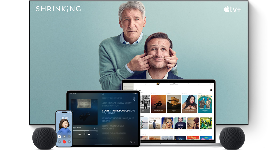 Large flat-screen television showing two male characters from the Apple TV+ series Shrinking. A MacBook Pro, an iPad, an iPhone and a Midnight HomePod mini are arranged in front.