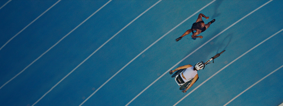 Two athletes about to race each other on the track. One of them has a prosthetic leg.