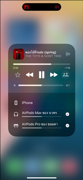 AirPods Pro ในเคสชาร์จที่วางอยู่ข้าง iPhone ในขณะที่ iPhone เชื่อมต่ออยู่กับ AirPods สองคู่โดยที่แต่ละคู่มีแถบควบคุมระดับเสียงของตัวเอง