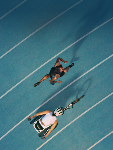 Two athletes about to race each other on the track. One of them has a prosthetic leg.