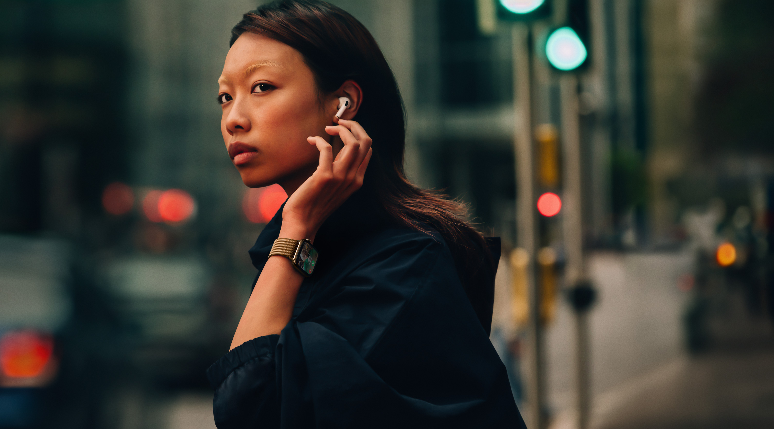 A woman on a street wearing Apple Watch Series 10 and AirPods.