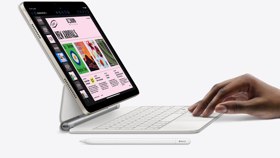 Skats no sāna uz iPad Air, kurā atvērta Keynote aplikācija un kam pievienota Magic Keyboard; uz skārienpaliktņa ir roka, bet blakus ir Apple Pencil.